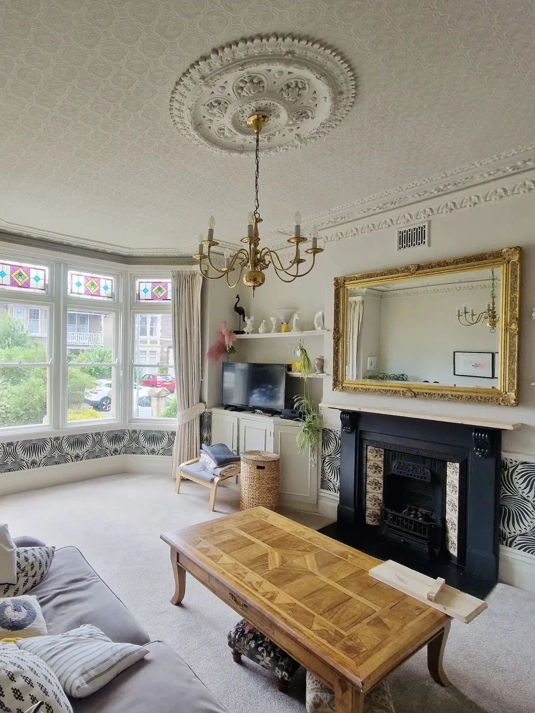 Finished period living room in a Bristol home with ornate ceiling rose, cornice, stained glass bay windows and a fireplace, decorated by Warrilow.